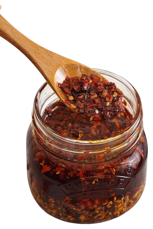 Glass jar of spice-infused chilli oil with a wooden spoon
